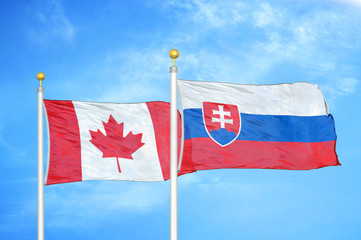 Canada and Slovakia two flags on flagpoles and blue cloudy sky