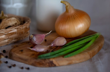 Garlic cloves, onion head and green onion feathers on wooden cutting Board. Useful products, antiseptics, natural medicine, healthy lifestyle. Close up. Selective focus.