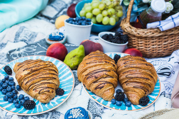 closeup of croissants on blue plates. still life with croissants. home garden picnic during isolation quarantine. easter at home. picnic at home. picnic decoration. picnic with croissants and fruits