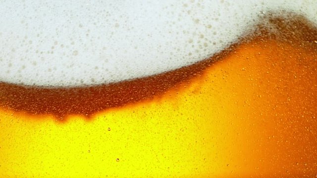 Super Slow Motion Detail Shot of Rippling Beer Bubbles and Foam in Glass at 1000fps.
