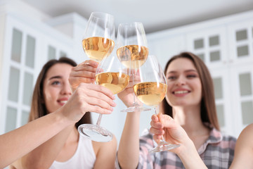 Beautiful young ladies toasting at home, focus on hands with glasses. Woman's Day