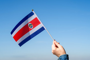 Woman hand with Costa Rica swaying flag on the blue sky. North America. Concept