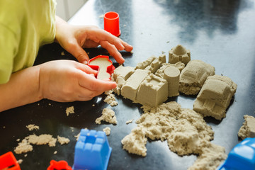 Cute little boy age of 3 years plays kinetic sand at home. Occupation with a child in quarantine.