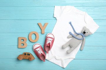 Flat lay composition with child's clothes, booties and word Boy on light blue background