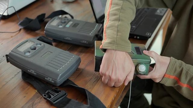 Closeup of biologist researcher hand preparing camera trap on work desk. Camera trapping is used to photograph animals for scientific purposes. Concept of environment, conservation, science, nature.
