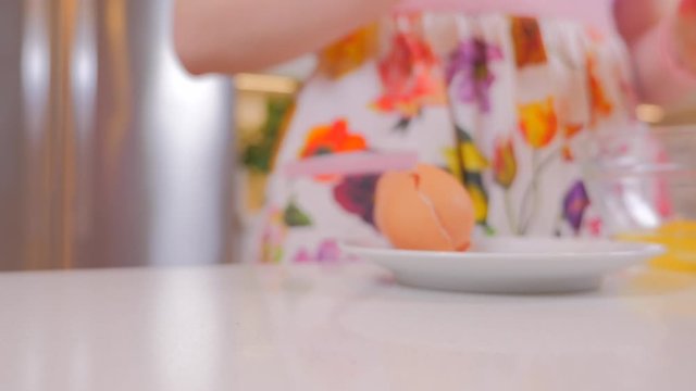 Woman cracking eggs into a glass bowl. Closeup of a pair of hands cracking an egg for cooking. Cook tasty food at home. Girl in a beautiful apron. 