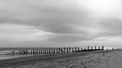 A moody black and white beach with a cloudy sky above