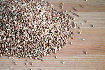 Heap of many buckwheat grains on wooden table surface indoors front view close up