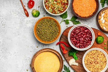 Various cereals and legumes. Beans, peas, lentils, mung bean, polenta and bulgur in bowls on a gray concrete background, top view, free space for text. Protein foods for vegans, copy space, flat lay.