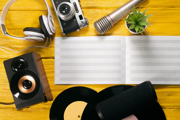 Retro vinyl record, music book, microphone and speakers on yellow flat lay background.