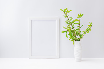 Home interior with decor elements. Mockup with a white frame and branches with green leaves in a vase on a light background