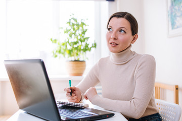 Fototapeta premium a young girl is working at home on a laptop. A foreign language teacher works remotely. Concept of distance work and online training