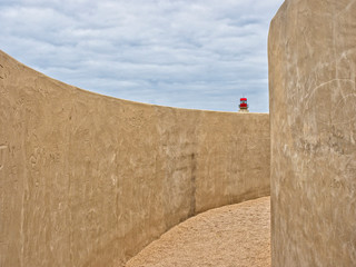 Muros en la fortaleza de Sagres con un faro al fondo