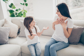 Fototapeta na wymiar Dream dreamy idyllic mother kid relationship small girl sit divan tell her mother funny funky school news she amazed shocked touch chest wear white t-shirt denim jeans indoors