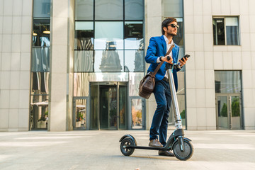 Businessman using cellphone while driving electric scooter near business center on city street © InsideCreativeHouse