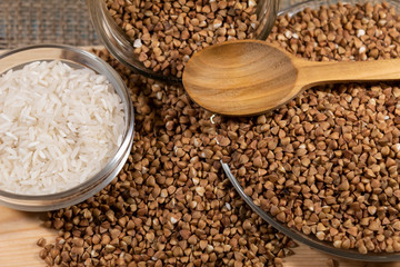 In the bowl is white rice. Buckwheat lies on a plate and is scattered nearby.