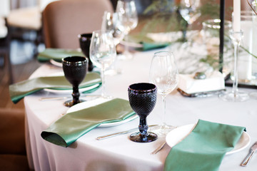 Festive wedding table setting with flowers, napkins, cutlery, glasses and candles, bright summer table decor. Wedding decor