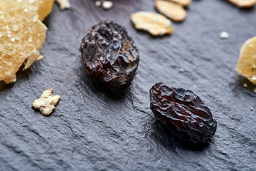 two raisins and oatmeal lies on a black rough surface. macro shot