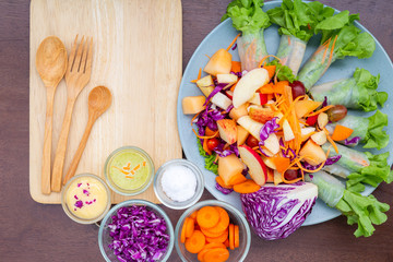 Delicious fruit salad in a clay brown dish on a cutting board with two dessert forks, mint leaves, on an old wooden table, close-up, top view
