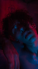 Portrait of man in shower with red and blue lights
