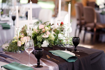 Festive wedding table setting with flowers, napkins, cutlery, glasses and candles, bright summer table decor. Wedding decor