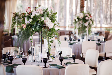 Festive wedding table setting with flowers, napkins, cutlery, glasses and candles, bright summer table decor. Wedding decor