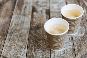 Two paper ribbed cups of freshly brewed aroma cappuccino with lush milk foam on wooden table...