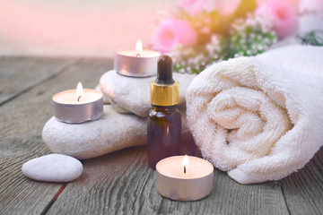 Aromatherapy concept with essential oil bottle, towel, burning candles and pebbles. Spa or herbal medicine still life compocition.