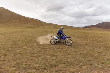 Motorcycle traveler man in helmet riding a motorbike in the steppes of Mongolia.