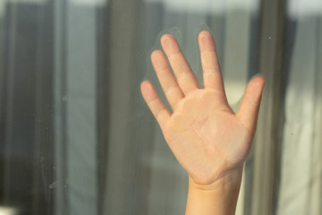 children's hand on glass window during quarantine self-isolation