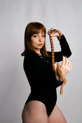 Beautiful woman in black bodywear and snake. Ginger model girl with fashion perfect make up.