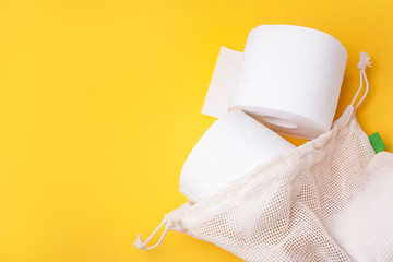 Fabric bag with rolls of toilet paper on a yellow background. Coronavirus concept. Quarantine. Flat lay stile