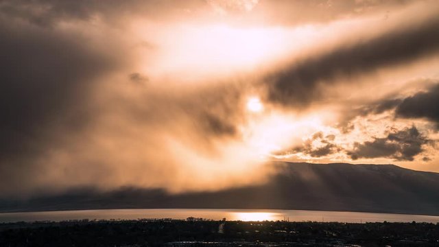 Time lapse of sun shining through rain during sunset as storm moves over Utah Lake.