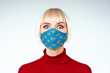 Shocked, surprised woman wearing handmade face mask. Copy, empty space for text