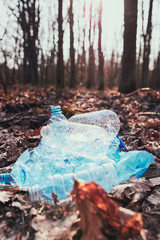 Fototapeta premium Plastic waste left in forest. Concept of plastic pollution and irresponsibility for environment. Environmental issue. Environmental damage