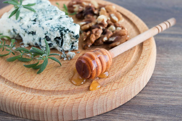 Blue cheese on a wooden serving board with walnuts and honey