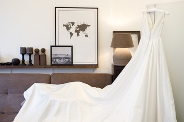 Bridal wedding dress hanging on hanger in the room in early morning.Wedding decor