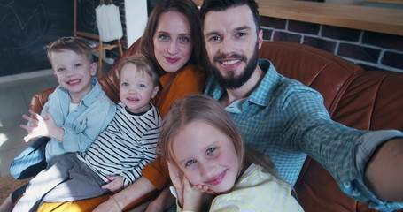 Fototapeta na wymiar Selfie family portrait, happy young Caucasian husband taking photo with wife and three children at home slow motion.
