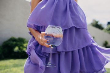 Copa con trago y hielos con modelo con vestido lila