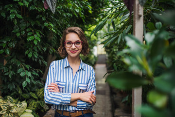 Young woman standing in botanical garden, looking at camera.