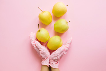 Hands in pink glove holding apples on pink background flat lay. Order groceries and get them...