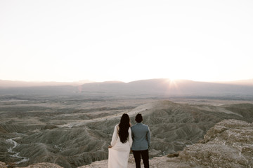 Fototapeta premium man and woman looking out across a desert vista as the sun sets