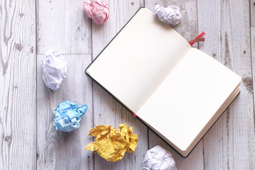 top view of crumpled paper ball and notepad on white background 