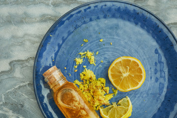 Yellow juicy Lemon, shredded Ginger and Honey on blue plate for homeopathic mixture to treat flu virus symptoms overhead shot