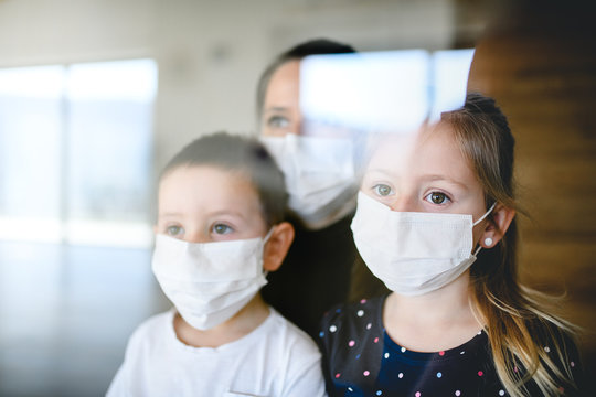 Mother and children with face masks indoors at home, Corona virus, quarantine concept.