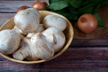 Mushrooms, spinach and onions on a wooden table