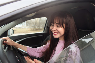 Fototapeta na wymiar Happy brunette in a car with a phone