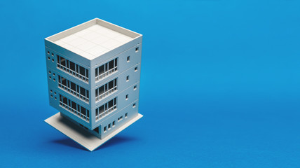 Model of a building balancing on one edge on a blue background