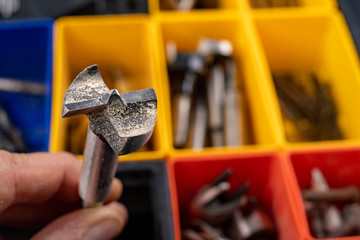 Wood drill against the background of other tools. Accessories for drilling in a home workshop.
