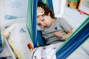 Little boy misses home playing phone sitting in hammock